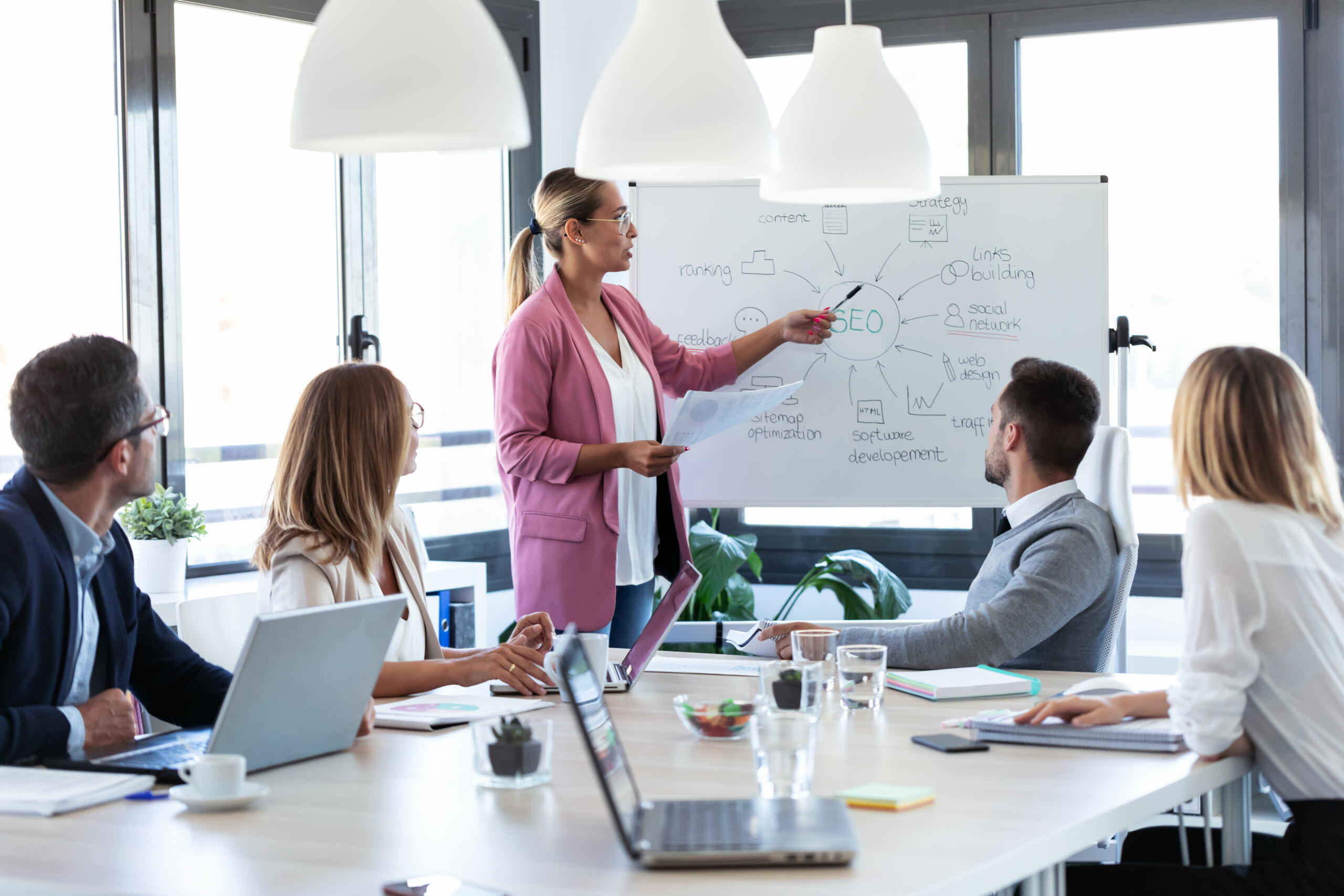 elegant young businesswoman pointing at white blackboard and exp